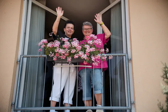 Mitarbeitende winken vom Balkon